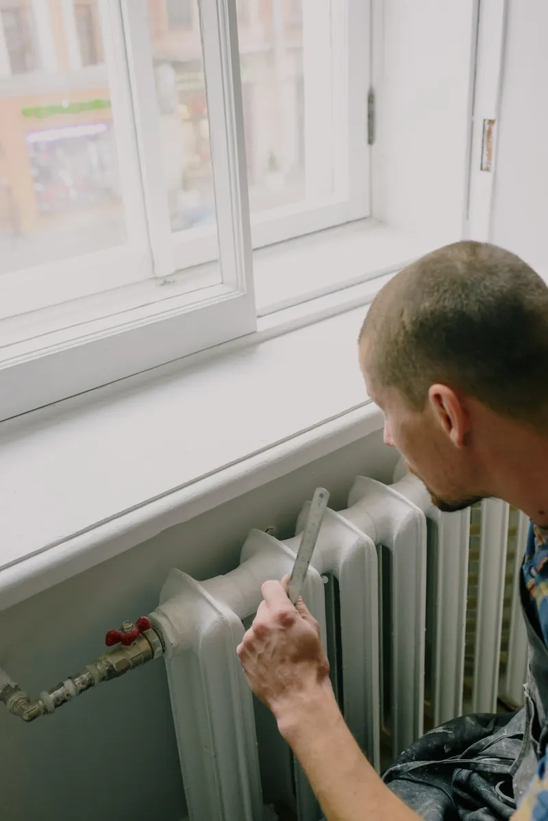 Professionnel intervenant près des raccordements d’un radiateur