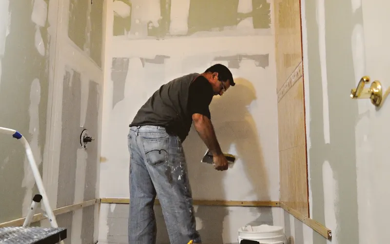 Professionnel préparant les murs d’une douche dans une salle de bains en rénovation